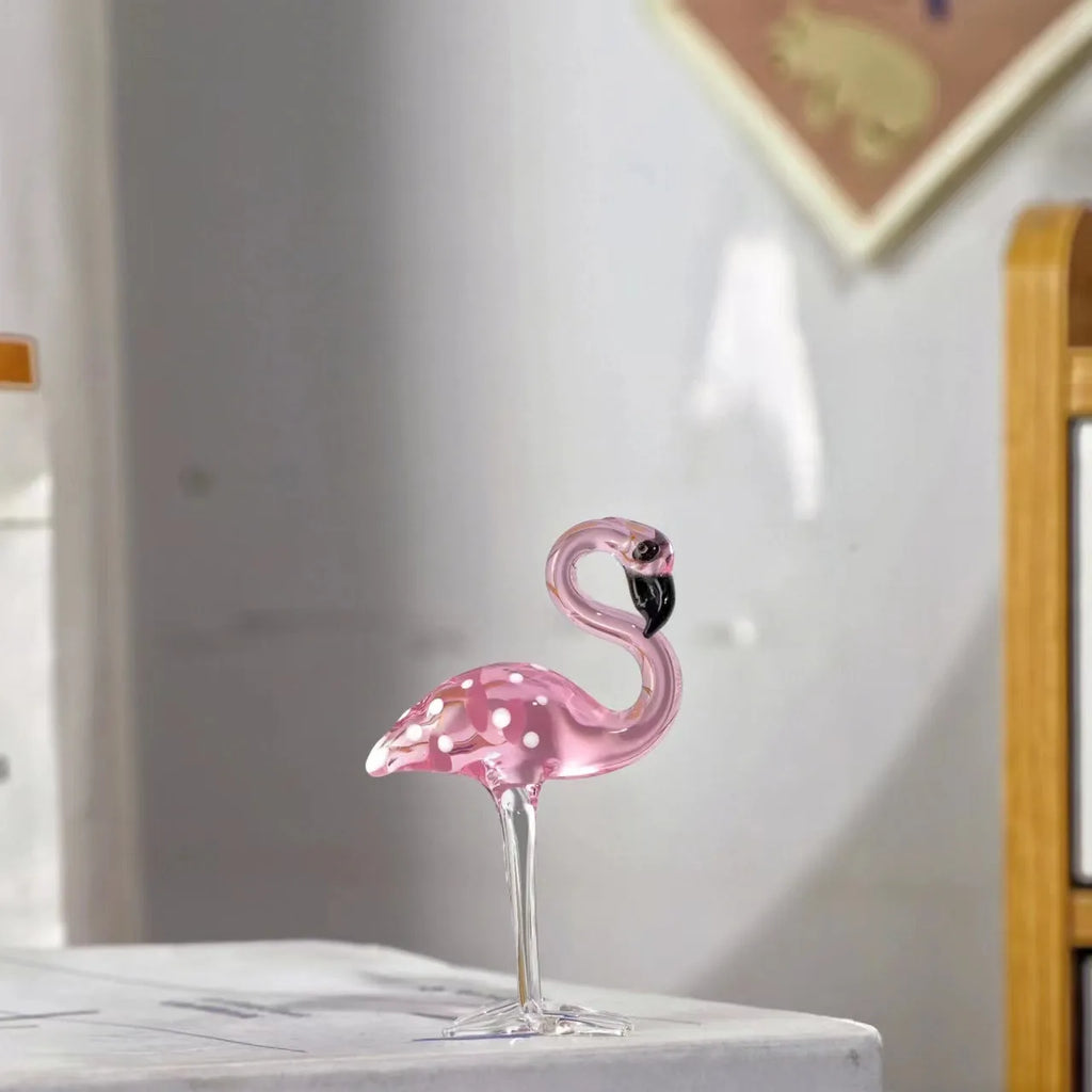 A pink flamingo decorative ornament made from clear white crystal on a table.