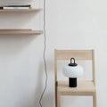 Minimalist clear glass bedside table lamp on a table in a child's bedroom.