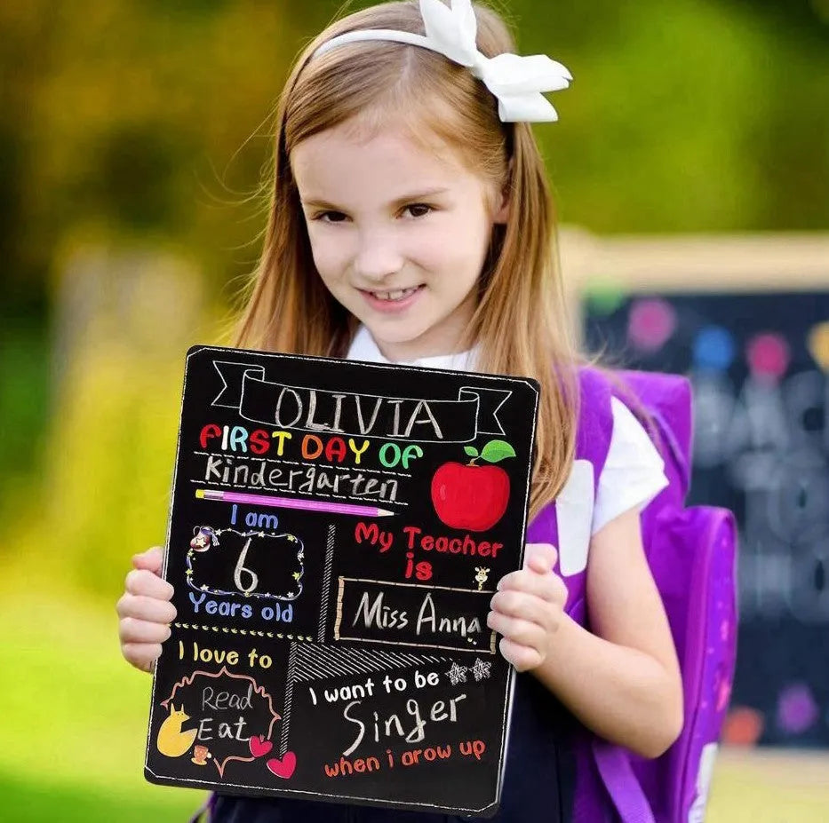 Black wooden First Day of School sign with white chalkboard text, measuring 25.5 by 30 centimetres.