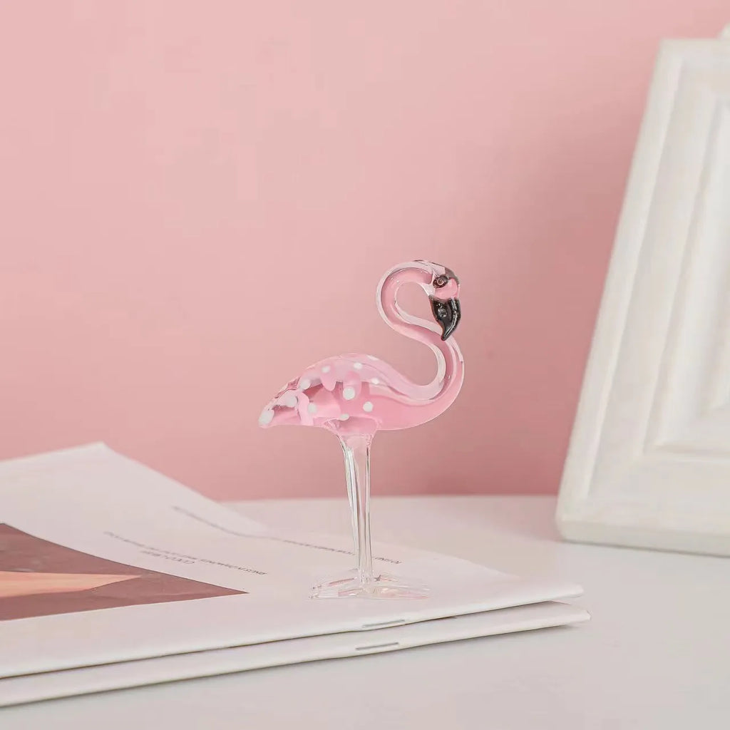 A pink flamingo decorative ornament made from clear white crystal on a table.