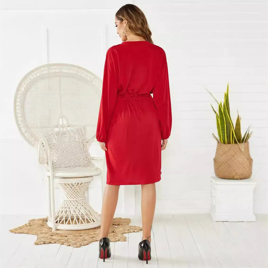 A woman wearing a red A-line midi dress with long sleeves, an elastic waist, and a cinched belt.