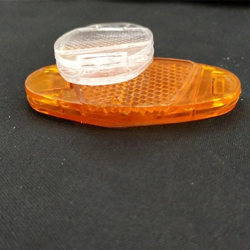 White and yellow plastic bicycle spoke reflector for wheel safety, dimensions 7.2cm long by 3.5cm wide.