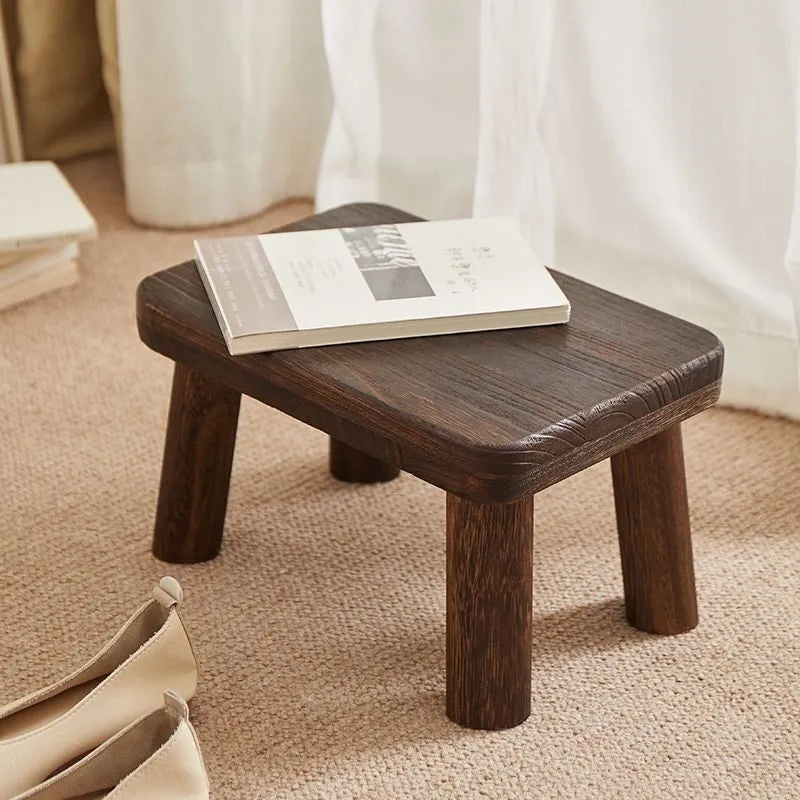 Solid wood household shoe changing stool with a distressed finish and bracket structure legs.