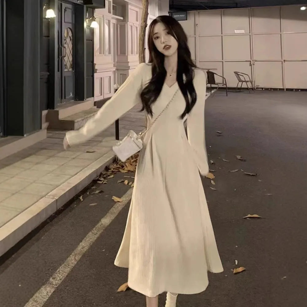 Women's milky white V-neck knitted long dress with princess sleeves on a hanger.