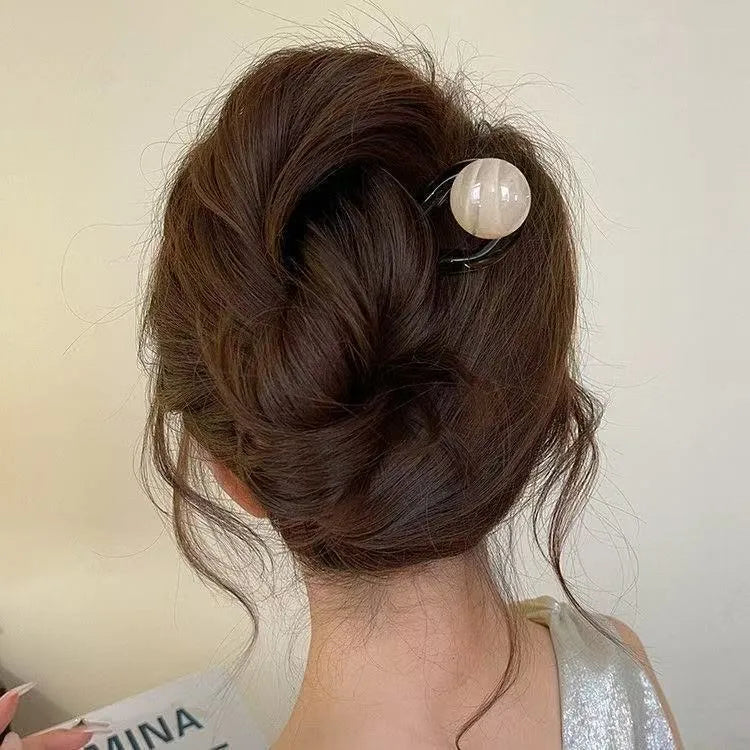 A set of simple U-shaped acrylic hair barrettes with a retro ball detail in beige and caramel colours.