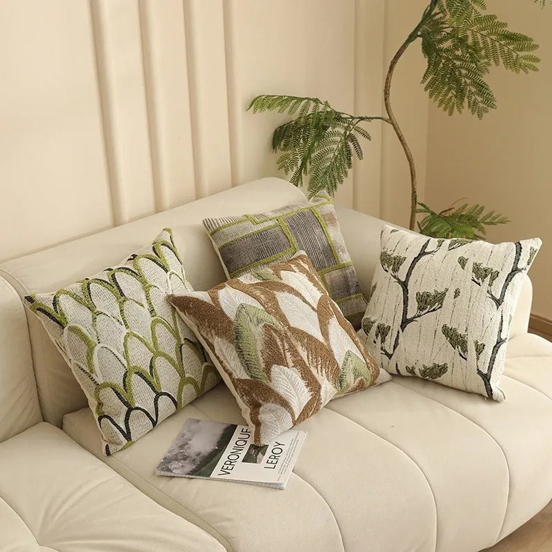 Square jacquard cushion cover with a detailed woven botanical pattern in a retro colour, shown on a grey sofa.