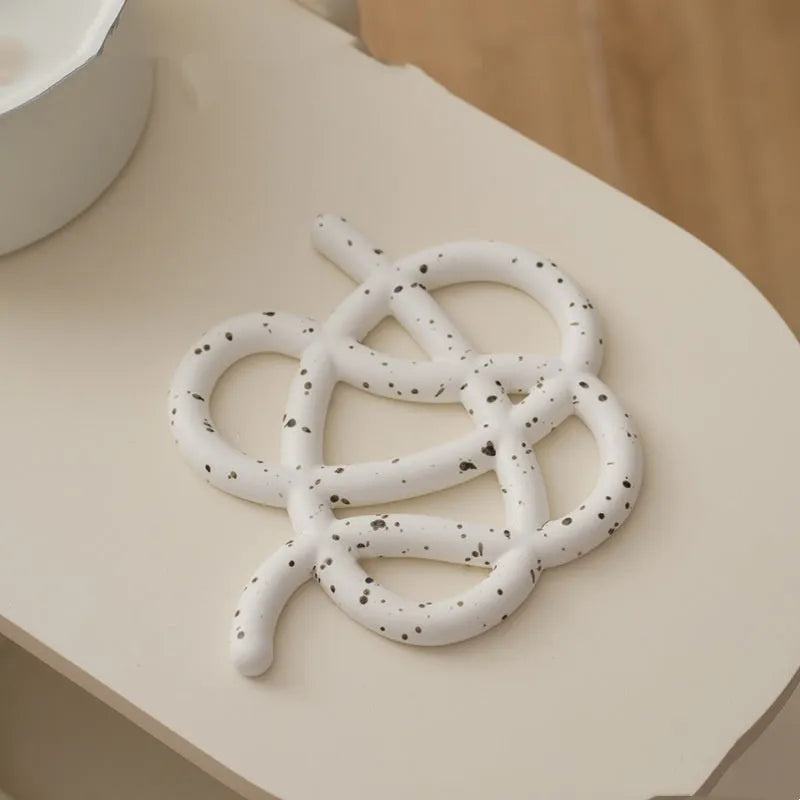 Ceramic heat proof mat in an irregular shape on a kitchen table, shown in a solid colour.
