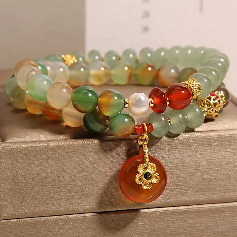 Gold-toned double ring chain bracelet with a peacock green agate safety buckle pendant and rhinestone details.