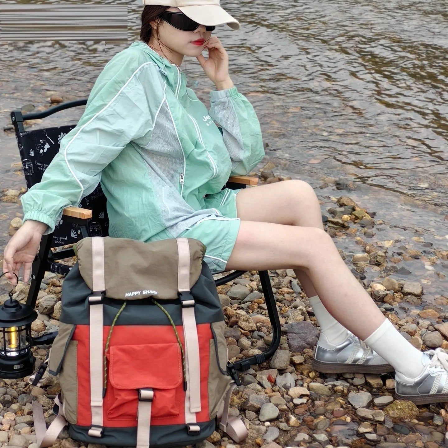 Orange and green contrast colour large outdoor backpack with multiple compartments on a neutral background.