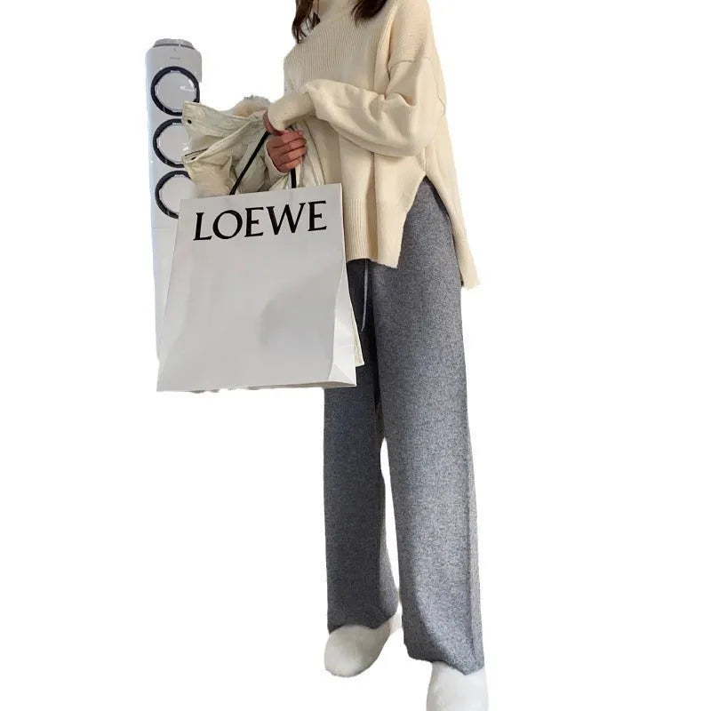 Woman wearing high-waist cream knitted wide-leg trousers with a floor-length, straight-leg silhouette.