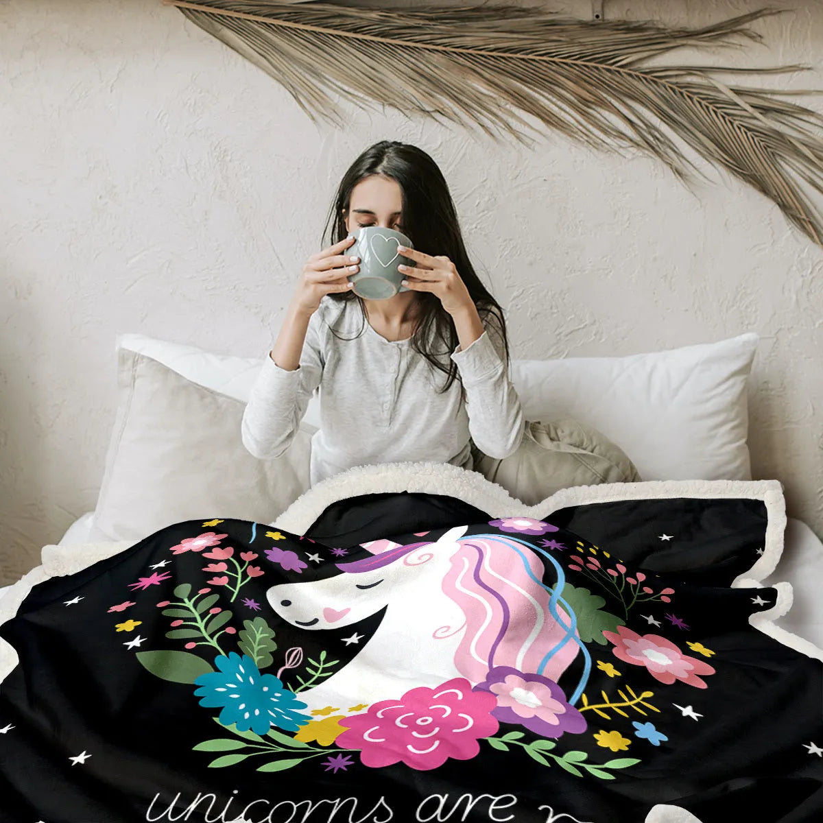 Black sherpa fleece blanket folded on a couch, soft fabric with hemmed edges.