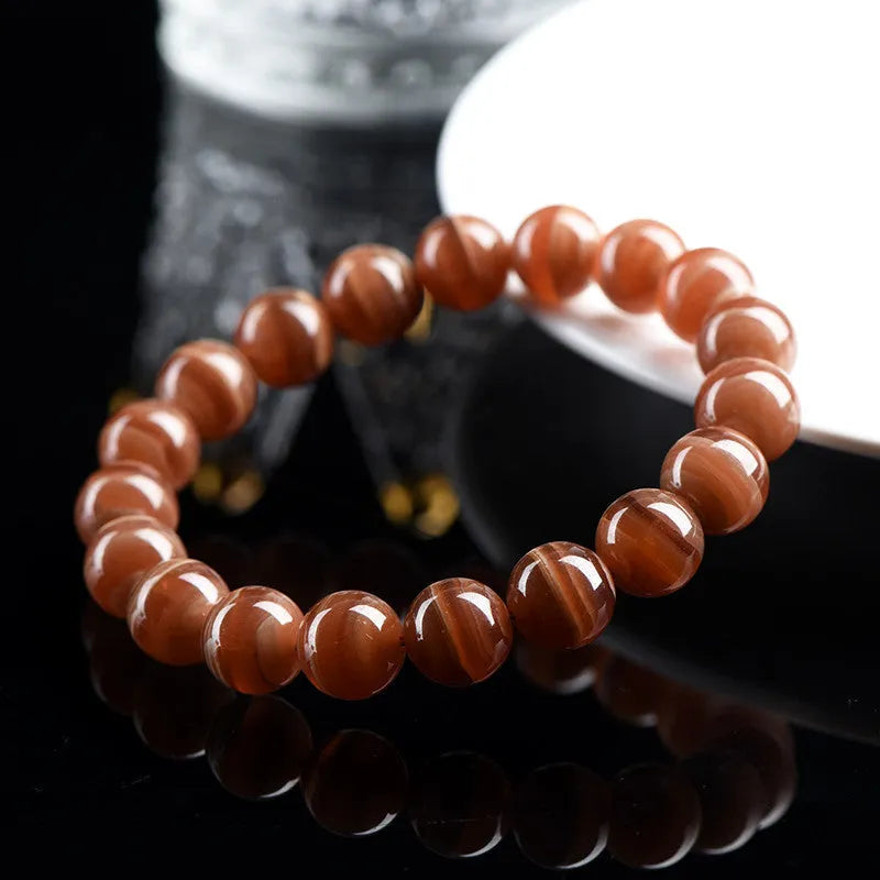 Natural old mine rhodochrosite round bead bracelet on wrist, showing geometric design and Ruyi symbol.