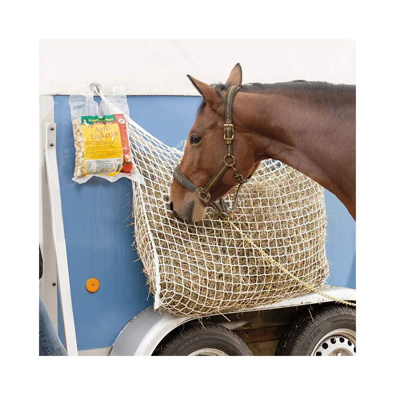 Black woven grid horse feeding bag hanging on a fence