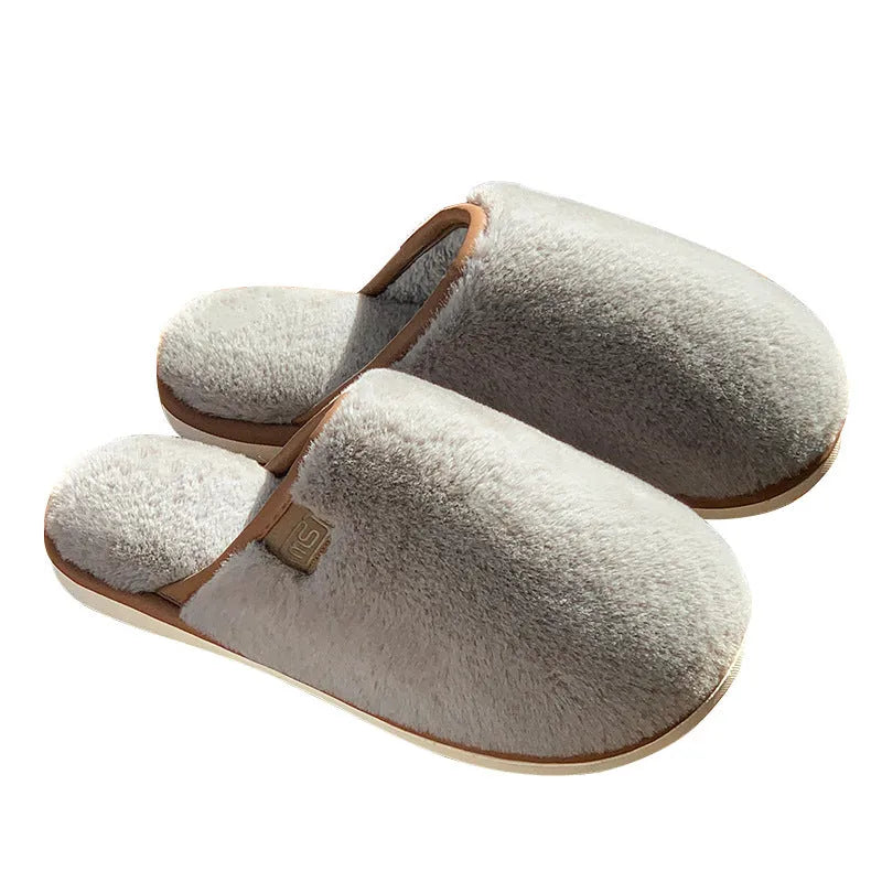 Blue plush slipper with non-slip PVC sole and car-stitching detail on a wooden floor.