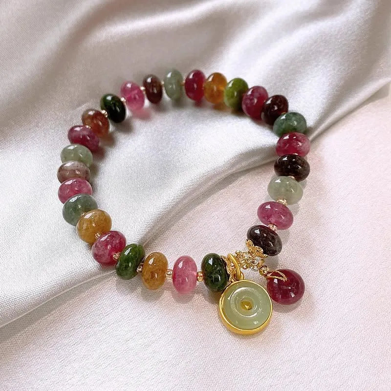 Colourful tourmaline beaded bracelet with geometric abacus beads and a rabbit pendant on a white background.