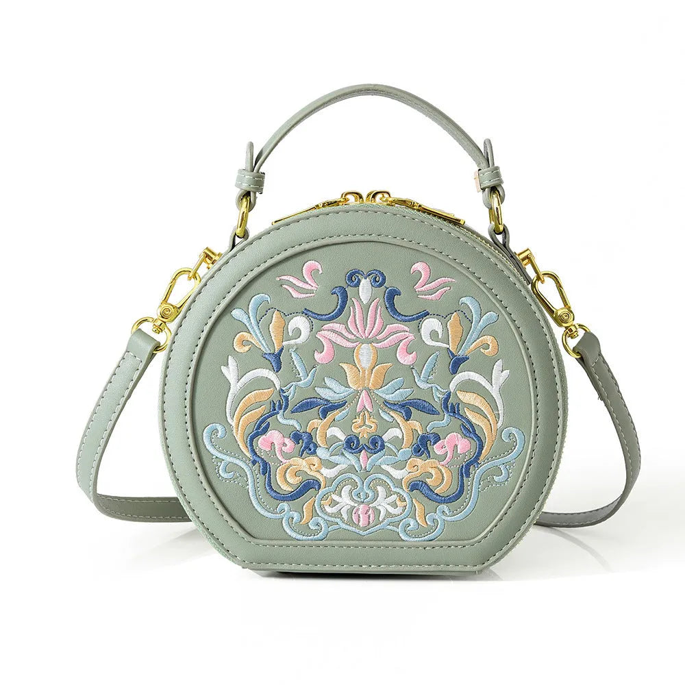 Small crossbody round bag in khaki with national-style embroidery and sewing line details, shown on a plain background