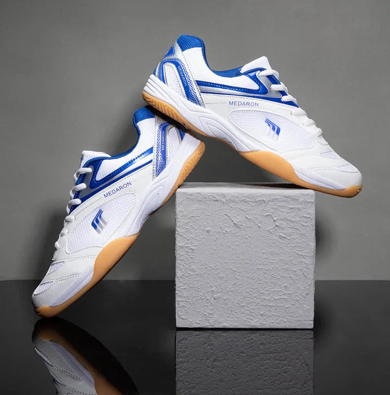White and red mesh table tennis sneakers with rubber sole and lace-up front.