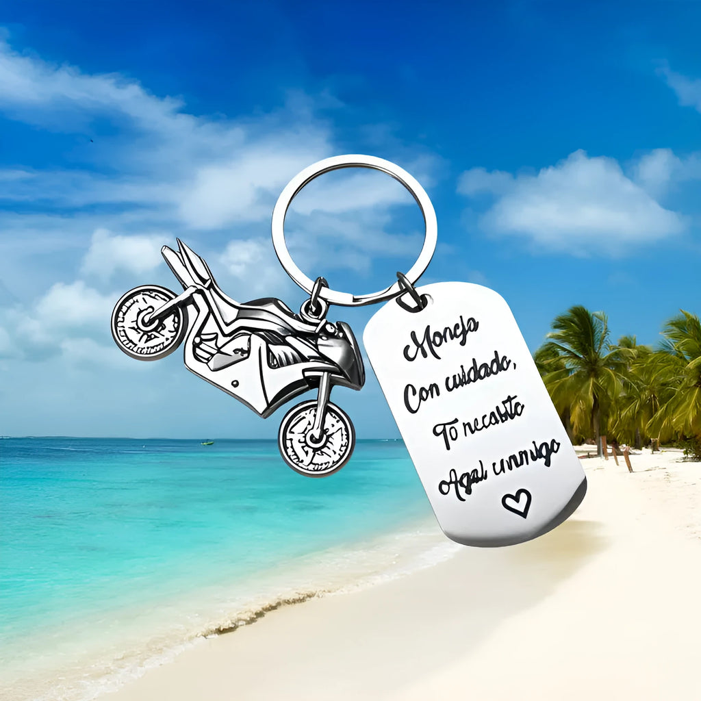 Stainless steel motivational motorcycle keychain with flannel storage pouch on a grey background.