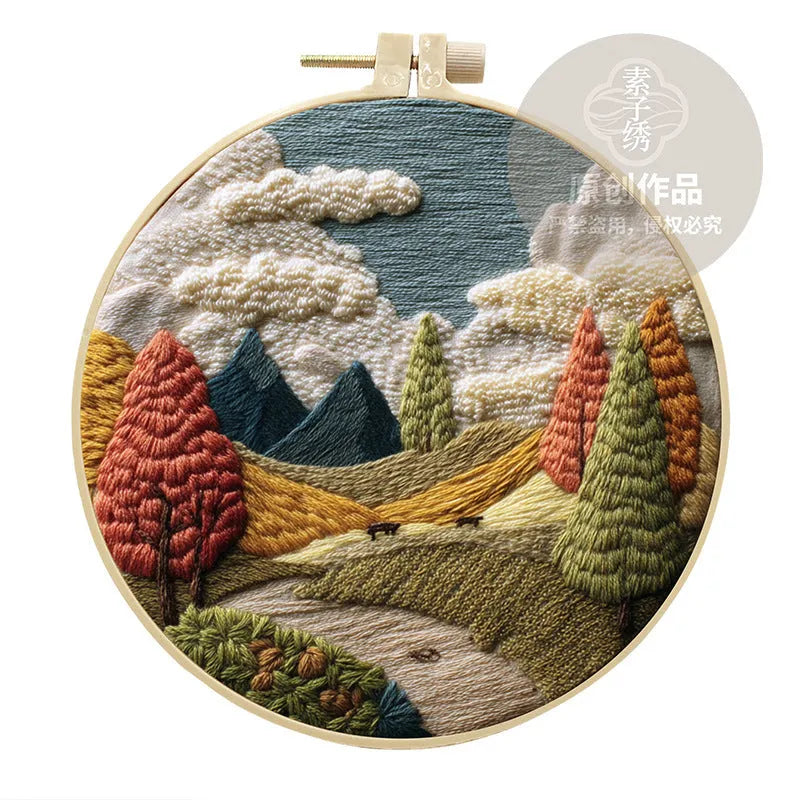 Complete DIY embroidery kit showing pre-printed landscape fabric, coloured threads, needles, and an embroidery frame.