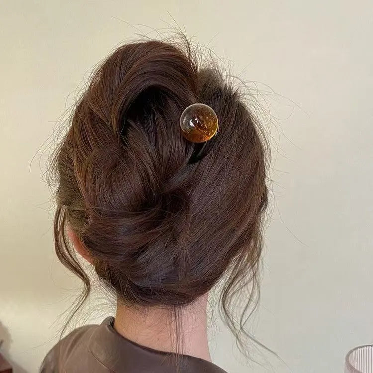A set of simple U-shaped acrylic hair barrettes with a retro ball detail in beige and caramel colours.