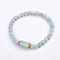 Close-up of a geometric jade bracelet with round emerald-coloured beads on a wrist.