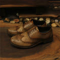 Men's light brown vintage distressed leather shoes with carved detail and round toe.