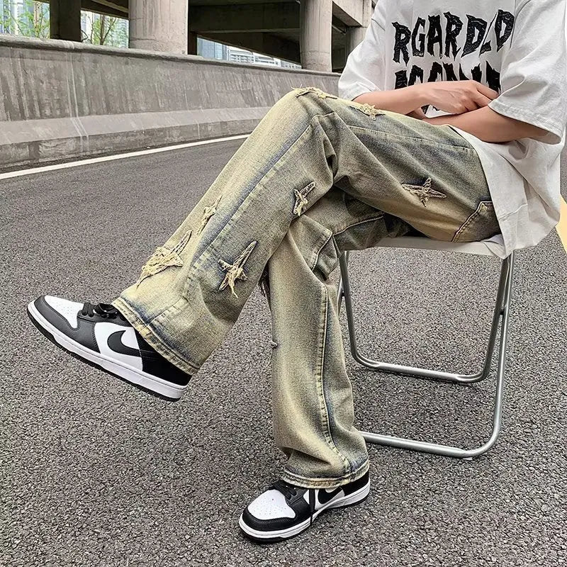 Men's loose denim trousers in black, straight-leg style with zipper fly, lying flat on a surface