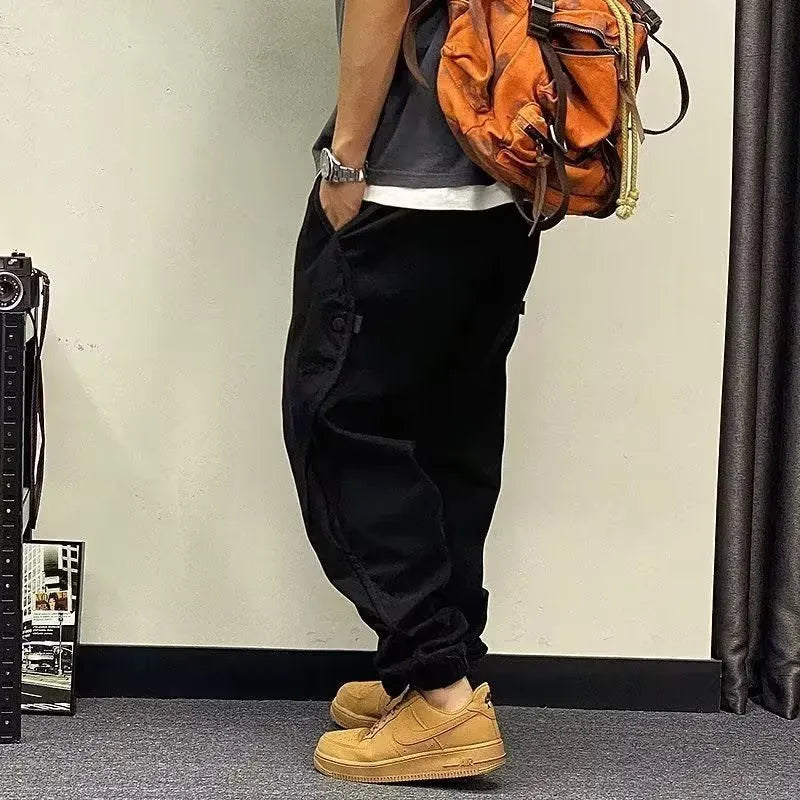 Men's black cotton harem pants with elastic waist and drawstring, cropped ankle bandage leg, side view