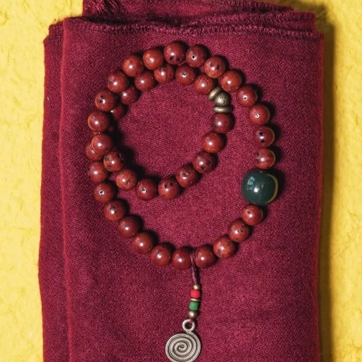 Handmade double circle charm bracelet strung with brown bodhi seeds on a white background.