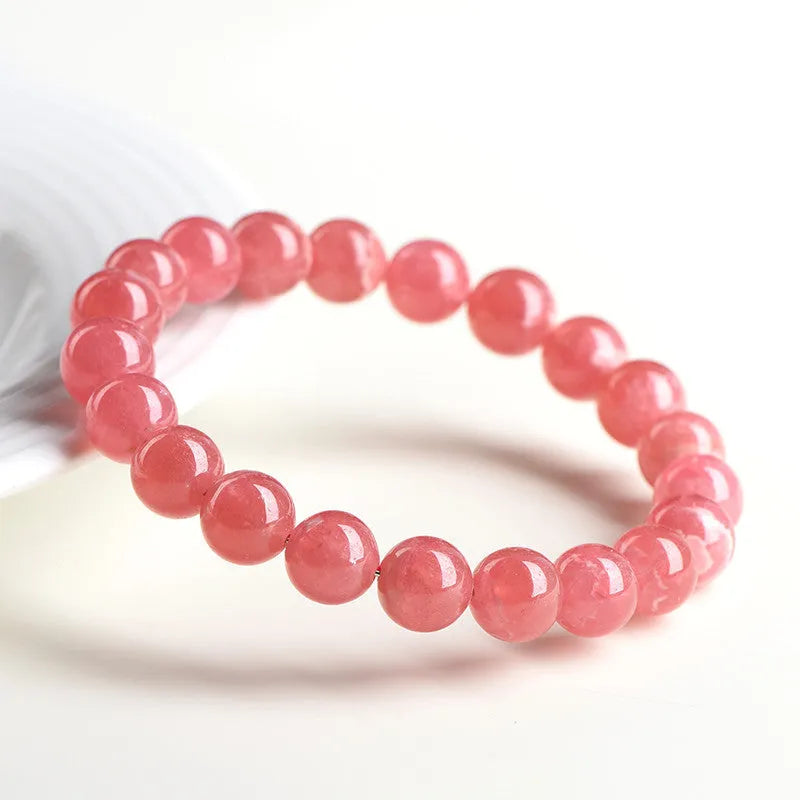 Women's red rhodochrosite crystal bracelet with geometric beads and longevity lock charm on wrist
