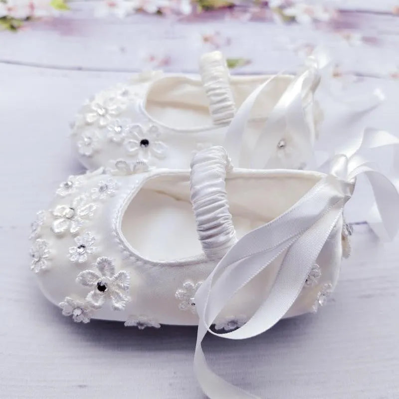 White baby soft bottom cloth princess shoes with rhinestone detail on a white background