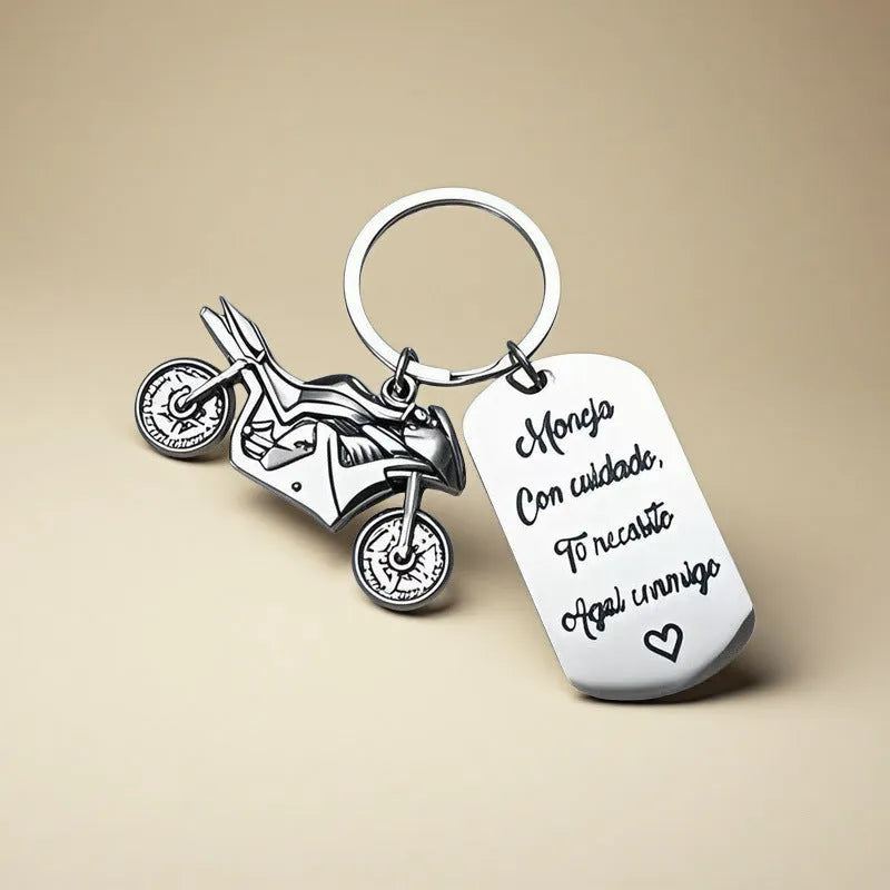 Stainless steel motivational motorcycle keychain with flannel storage pouch on a grey background.