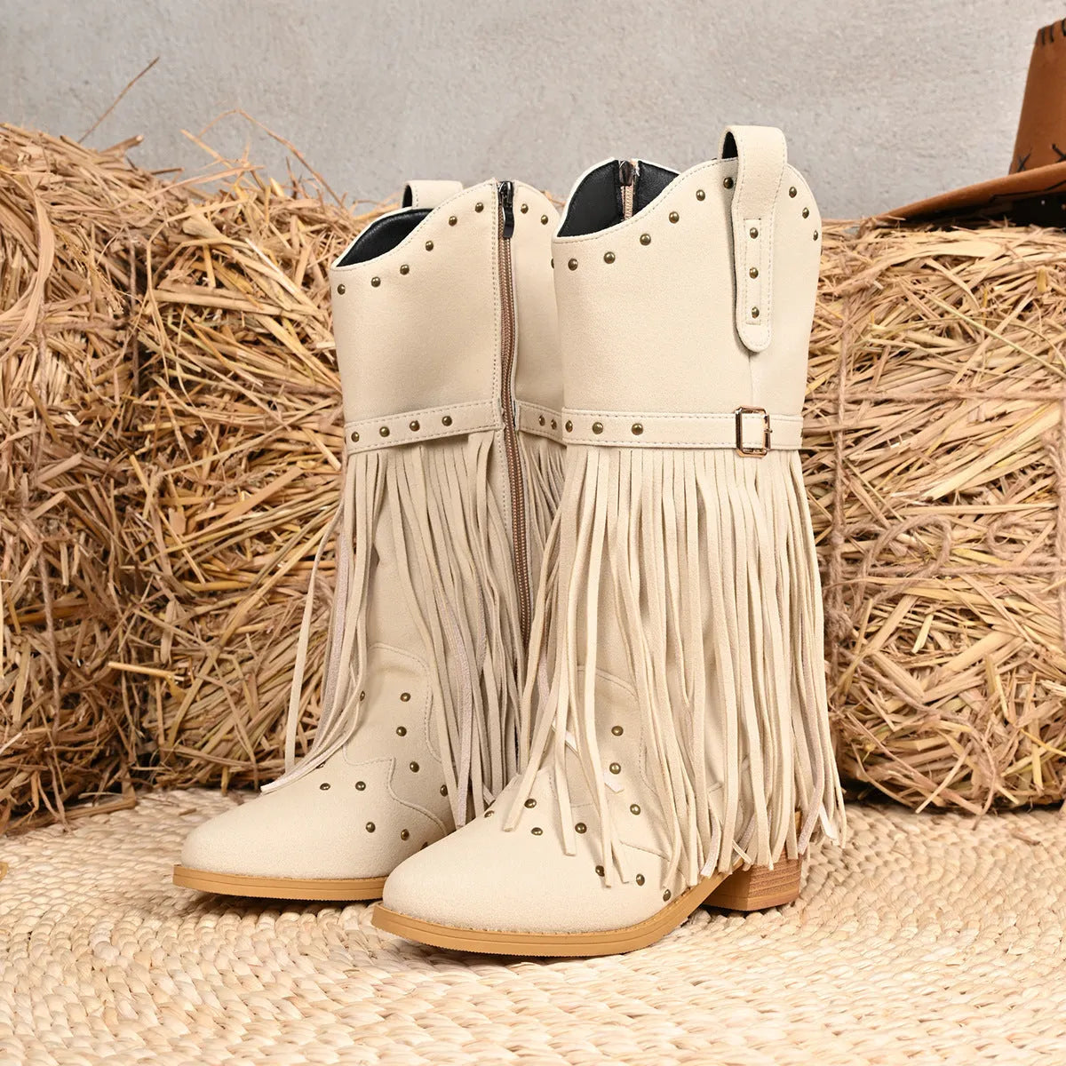 Beige women's western cowboy boots with mid heel, side zipper, and tassel details on a white background