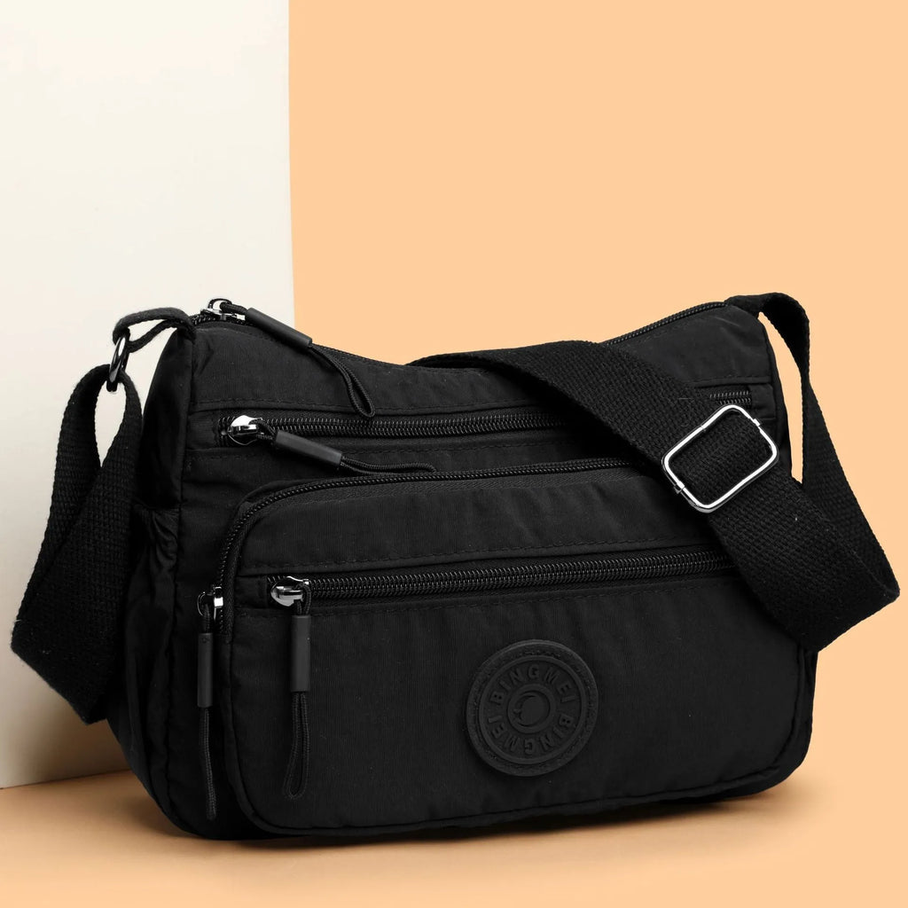 Grey water-repellent nylon crossbody bag showing three-dimensional pockets and a single shoulder strap.