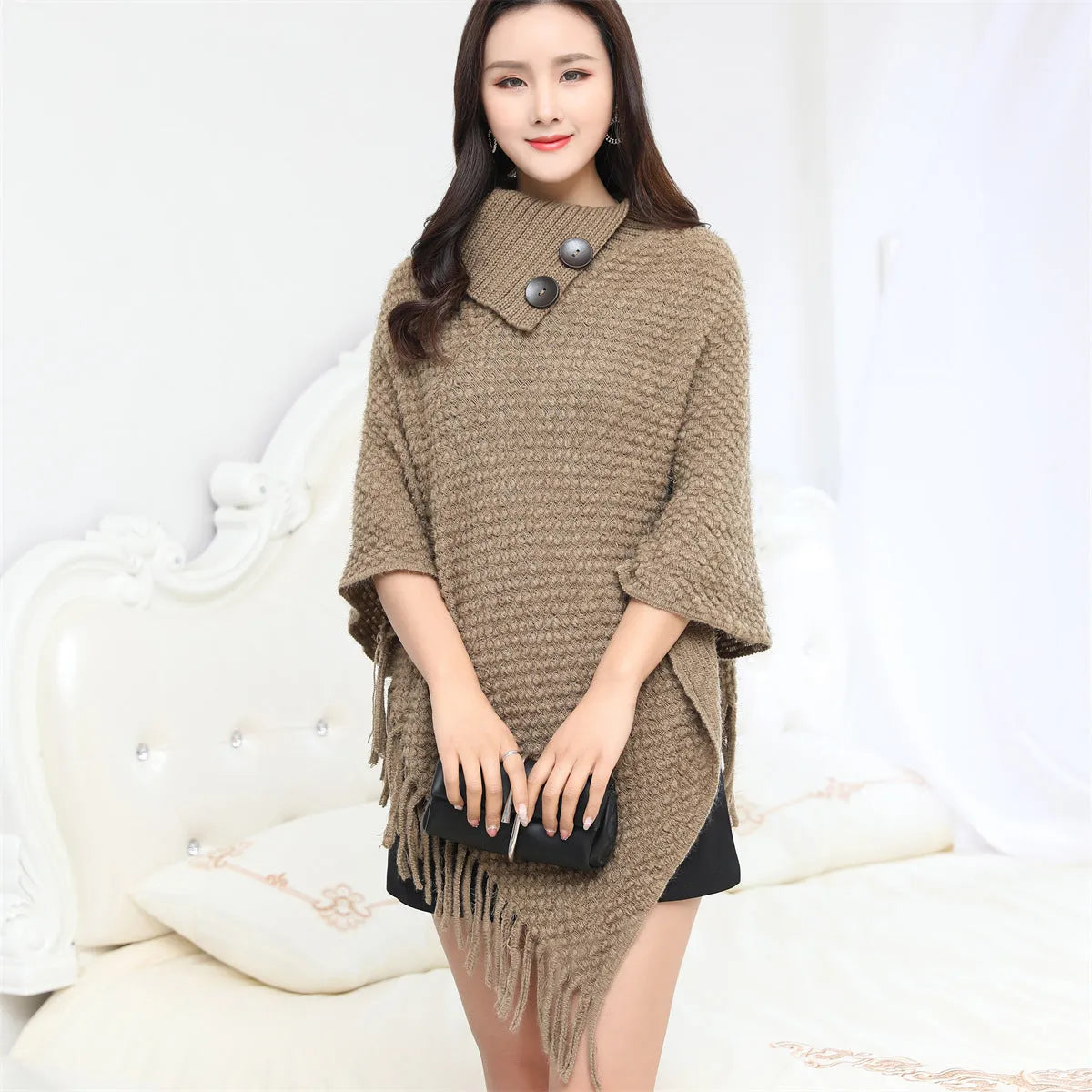 Sleeveless dot pattern knit cloak poncho in apricot colour, laid flat.