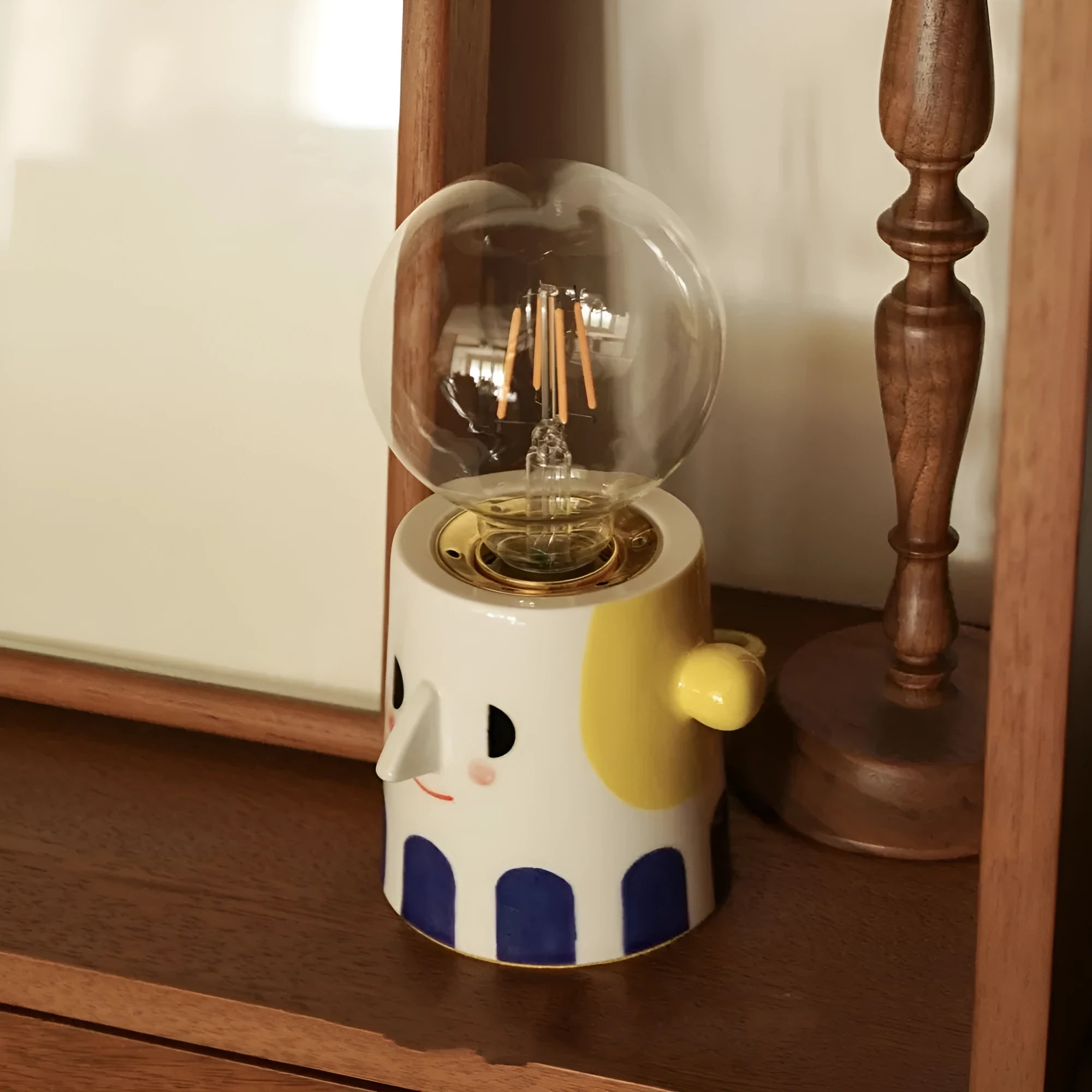 Handmade ceramic bedside lamp with a creative ball headlight design on a wooden table.