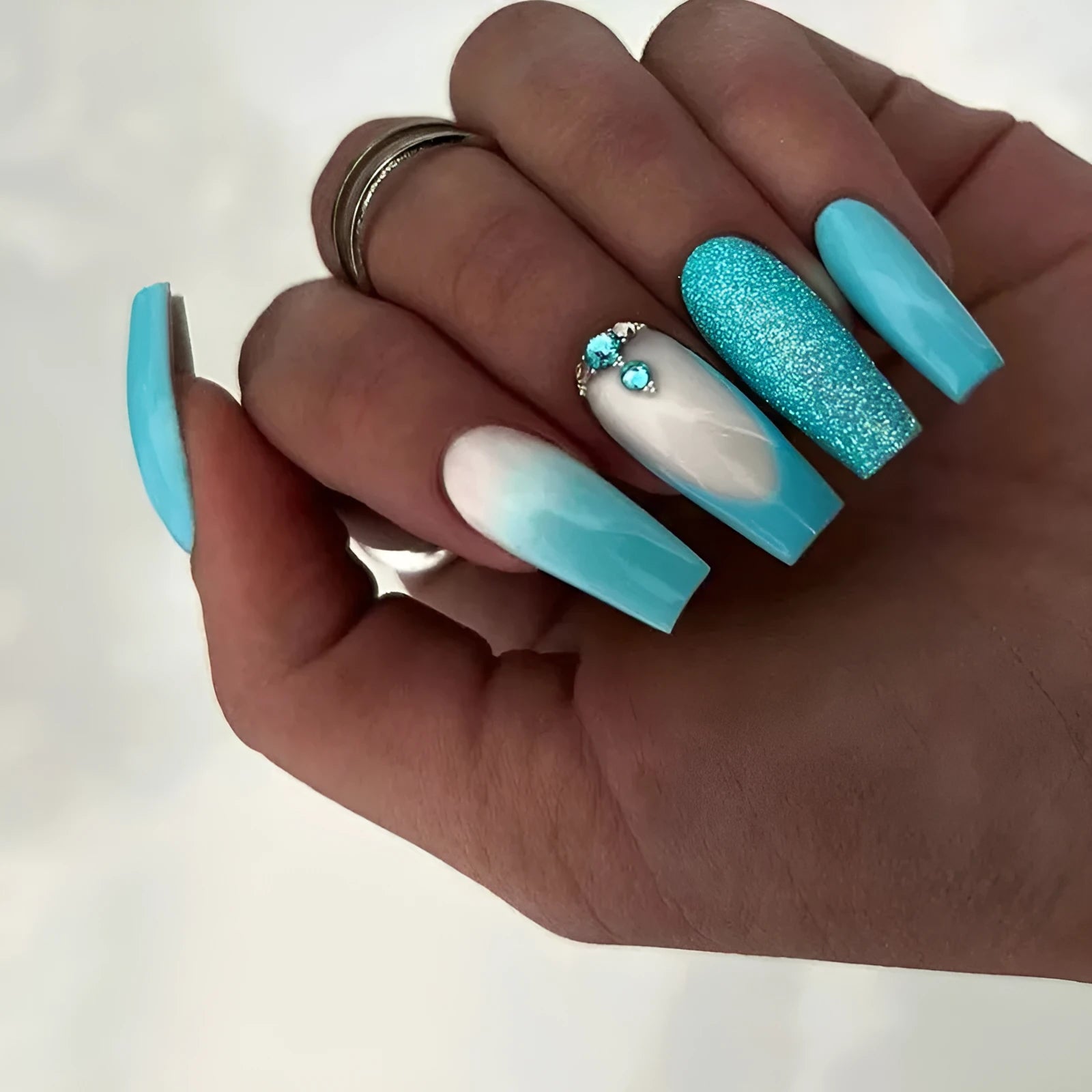 Solid colour artificial nails with smart blue diamond accents and ballet-length cut