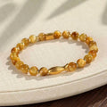 Women's tiger eye bracelet with small gold fish charm on adjustable band