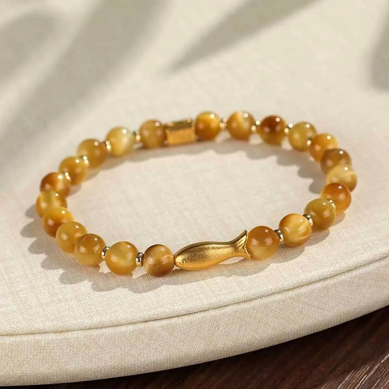 Women's tiger eye bracelet with small gold fish charm on adjustable band