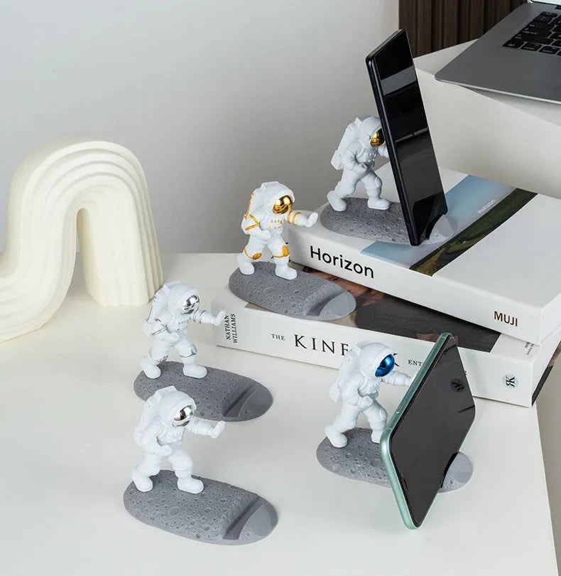 Plastic astronaut decoration mobile phone holder in blue colour on a desk
