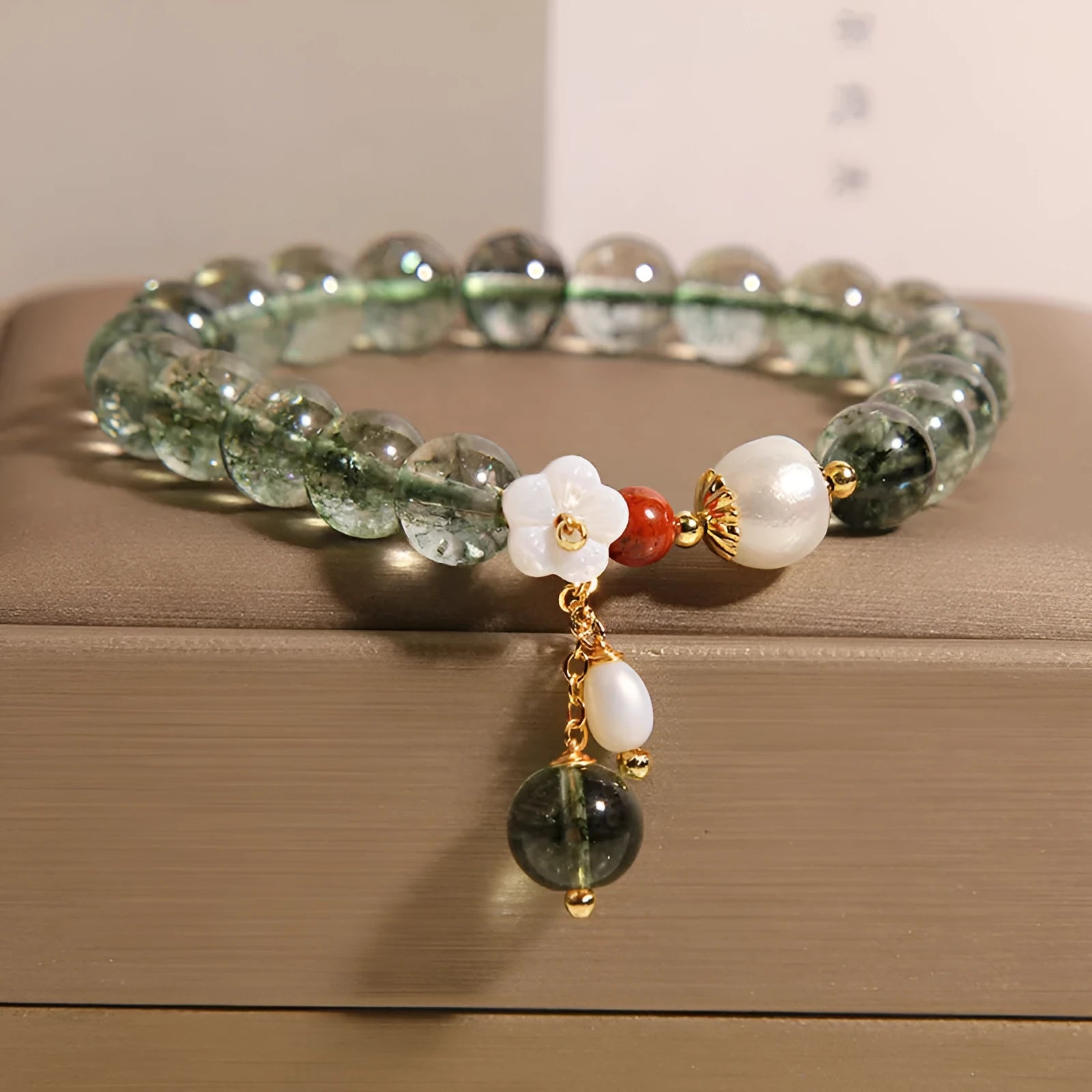 Green phantom quartz crystal bracelet for women with a small white shell flower accent.