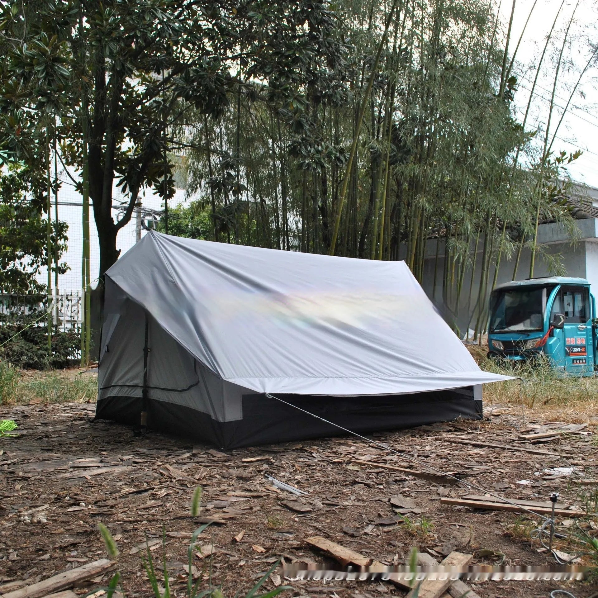 Lightweight brown A-line hiking tent set up with hiking cane supports in outdoor setting