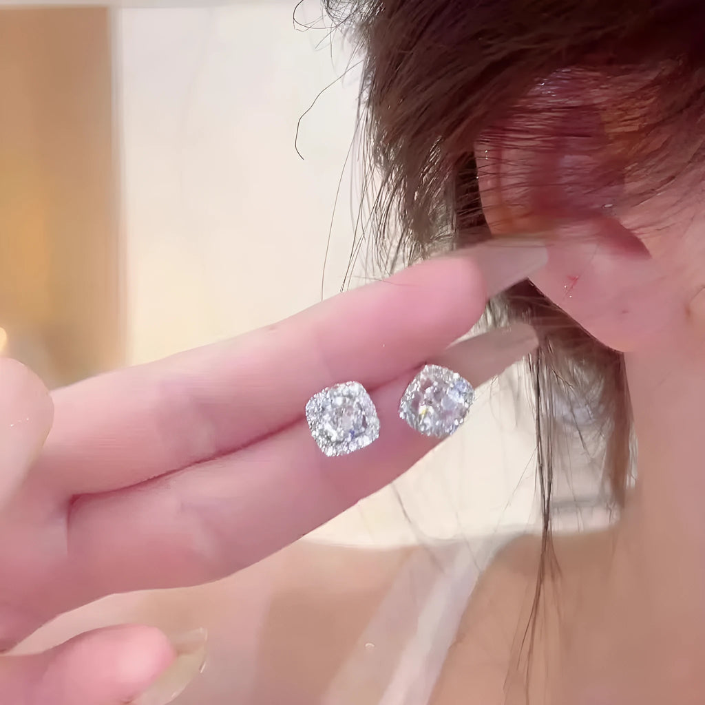 A pair of square, geometric diamond-treated alloy earrings in a gold colour on a white background.
