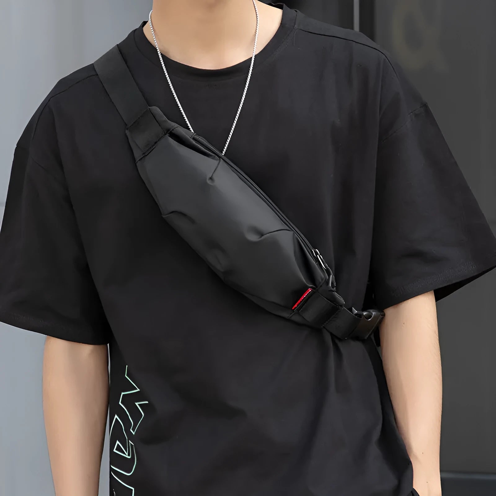 Black Oxford cloth waist pack for men worn crossbody, showing front zip and compact size.