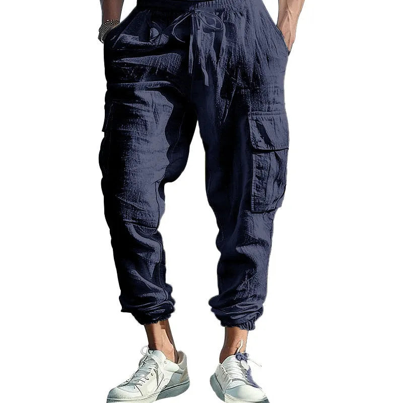 Man wearing loose khaki linen trousers with ankle-tied cuffs, drawstring waist, and multiple pockets.