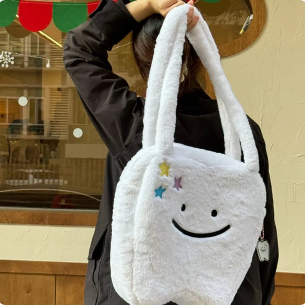 White plush tote bag with a cute teeth graphic, showing the crossbody strap and zipper opening.