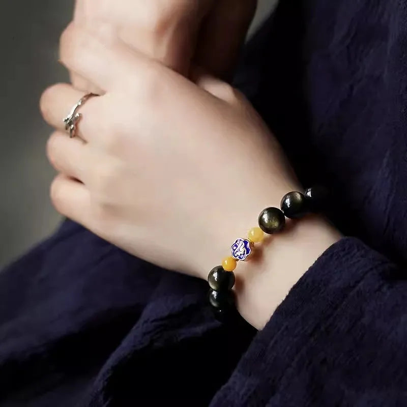 Golden obsidian bracelet with carved zodiac symbols on geometric beads