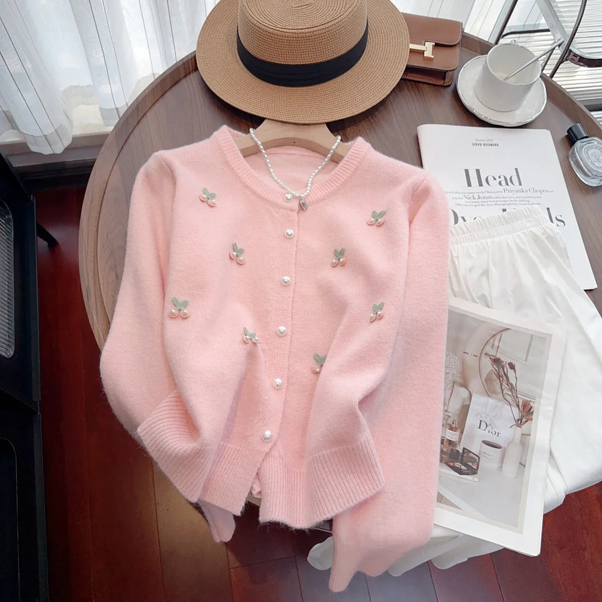 Women's soft pink cashmere blend cardigan coat with beaded detail and round neck, laid flat.