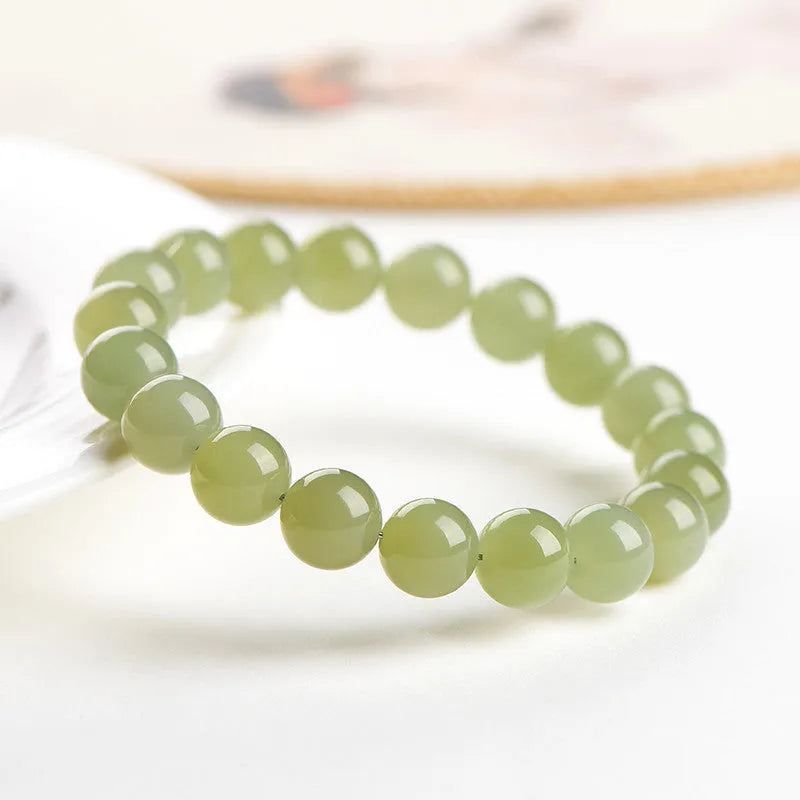 Polished Hetian jade beaded bracelet on a wrist, showing ice-like clear colour tones and spherical beads.
