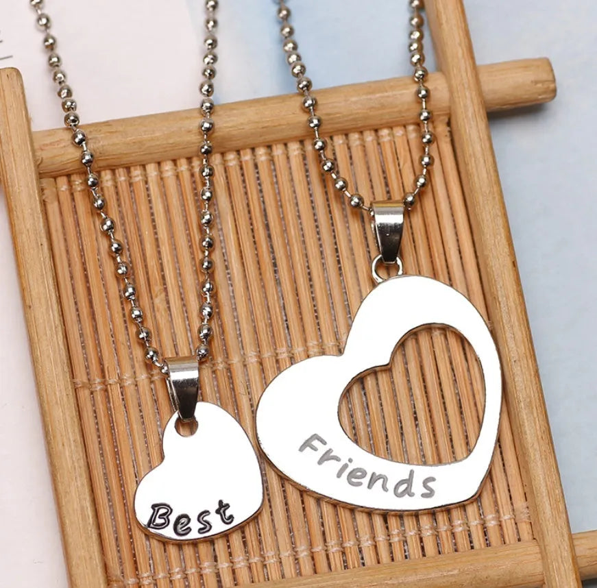 Two matching silver heart-shaped cross chain necklaces on a surface, alloy construction